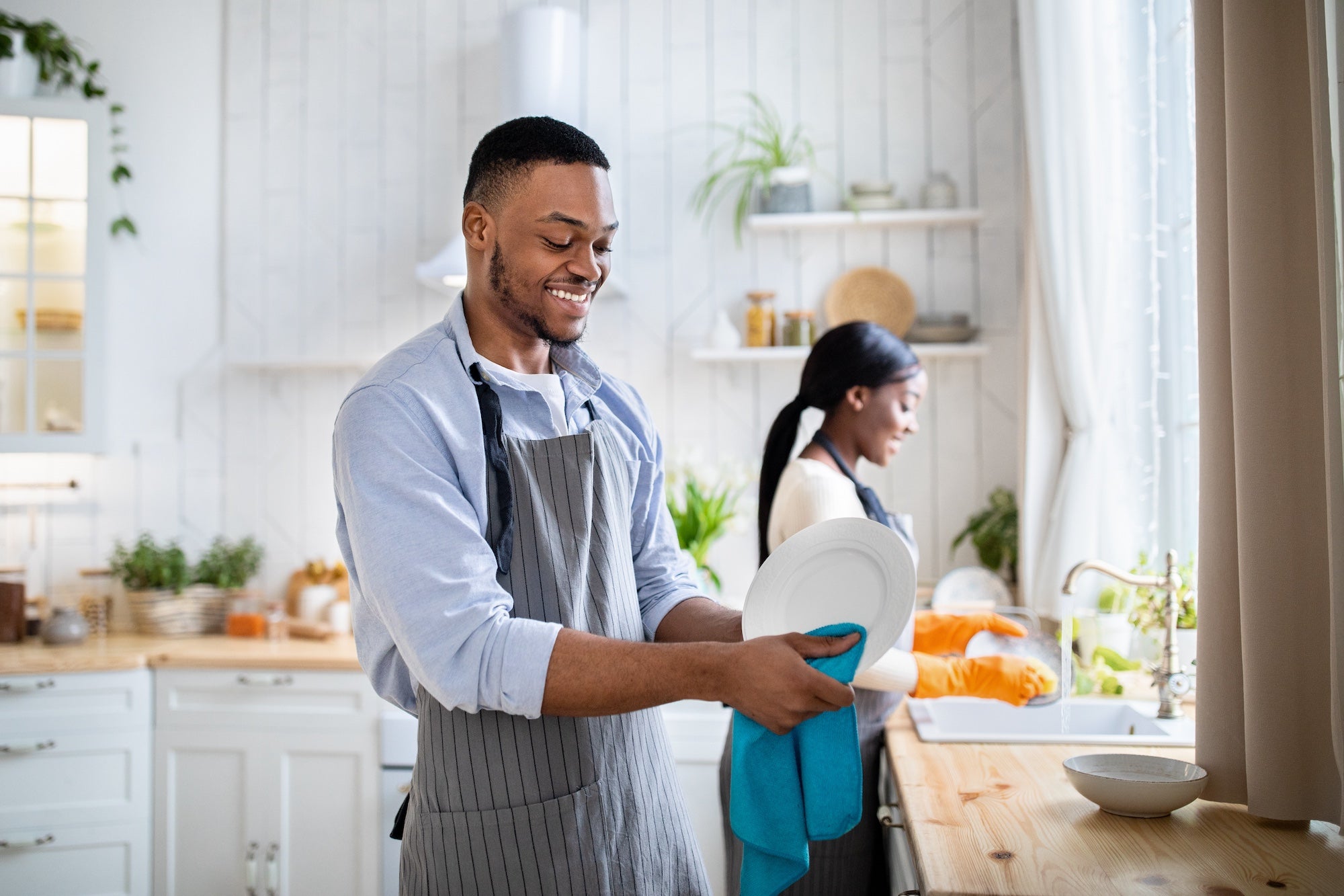 cheerful couple washes dishes together in a well lit kitchen