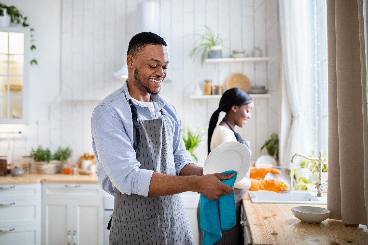 cheerful couple washes dishes together in a well lit kitchen